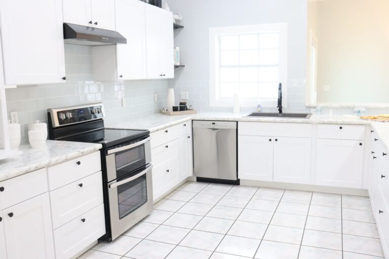 A bright and spacious modern kitchen with white cabinets, appliances, and natural light.