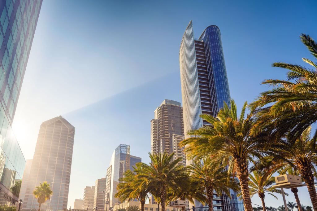 San Diego cityscape featuring modern skyscrapers and palm trees under a clear blue sky.
