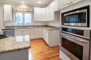 Clean spacious modern kitchen with white cabinets and granite countertops.